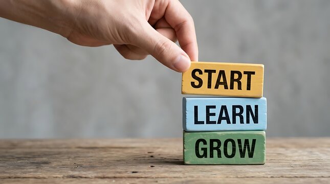 Person placing a yellow block inscribed with start on top of learn and grow blocks representing business strategy career development and self growth concepts.