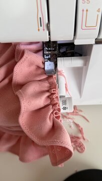 Aesthetic sewing workspace with an overlock machine, serger, fabric, threads and sewing accessories. Cozy atmosphere, the art of sewing, handmade fashion and garment making in a bright sewing studio