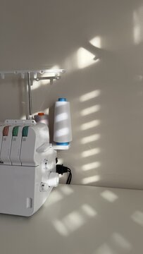 Aesthetic sewing workspace with an overlock machine, serger, fabric, threads and sewing accessories. Cozy atmosphere, the art of sewing, handmade fashion and garment making in a bright sewing studio