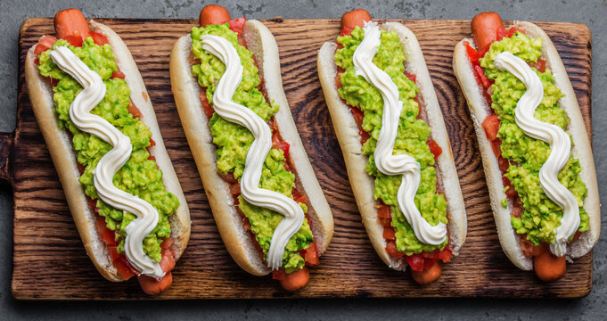 Chilean Completo Italiano. Hot dog sandwiches with tomato, avocado and mayonnaise on wooden board. Top view.
