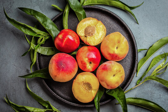 Fresh peaches on black plate, gray slate background. top view