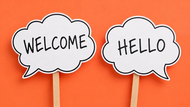 Two White Speech Bubbles With Welcome And Hello Text On Sticks Over Orange Background, Friendly Greeting Concept For Business Reception