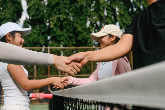 Cropped of Tennis Players Shaking Hands Over Net After Match &mdash; Sportsmanship and Respect in Doubles Game