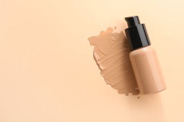 Swatch and bottle of liquid foundation on beige background, top view. Space for text