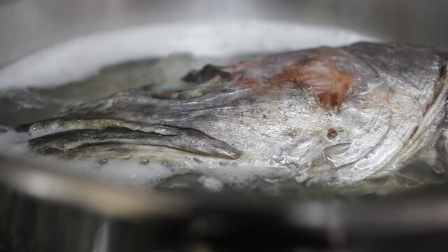 Overhead shot of hake head boiling in pot for fish broth