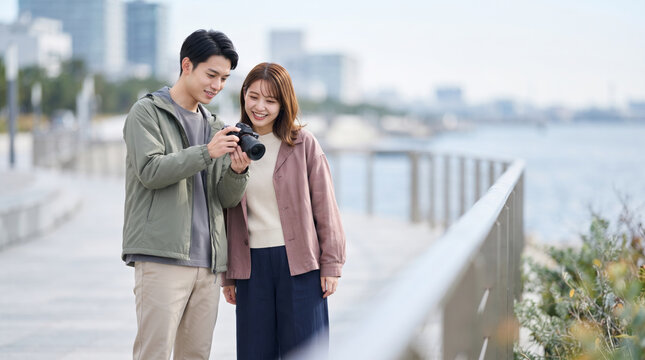 旅行先で一眼レフカメラの画像を確認する若い男女カップル