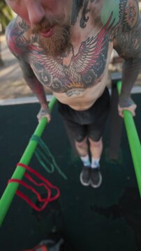Man performs exercises on parallel bars in a park