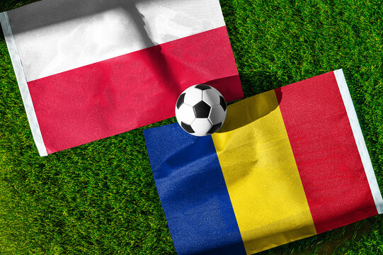 Poland vs. Romania football match. National flags on green grass with soccer ball in the middle. Football background for international match.