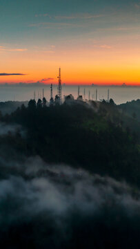 Aerial view of communication towers on a misty mountain ridge at sunrise in Tosari, East Java, Indonesia.
