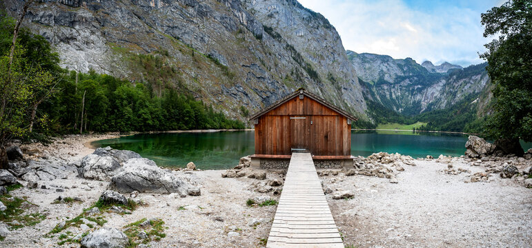 Scenic wooden boathouse on a pristine lake with towering mountains reflecting in the clear turquoise water