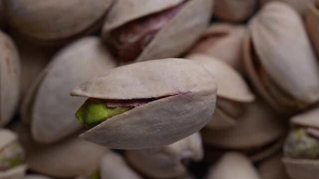 Macro view of pistachio nuts in natural shell showing green kernel healthy snack ingredient and organic food concept, rotates