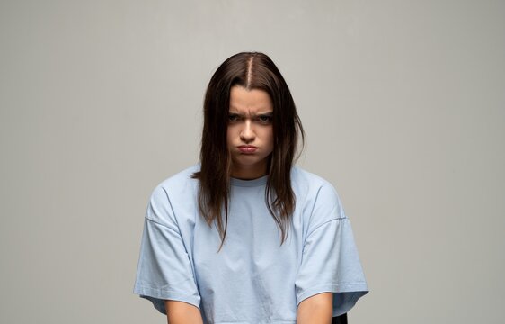 Young woman having an angry, upset, and frustrated facial expression, pouting lips and frowning brow with bad mood