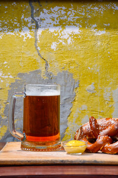 beer pretzel and mustard on a wooden table. rustic oktoberfest drink and food background. grungy wall texture. vertical view