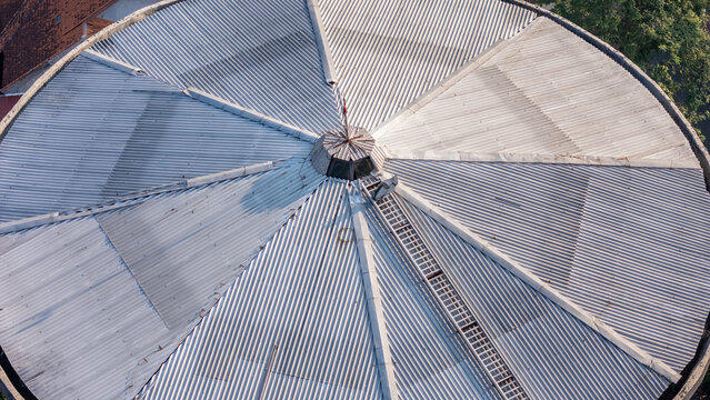 Aerial view of a circular corrugated metal roof with a central ventilation structure and a maintenance ladder in Klaten, Central Java, Indonesia.