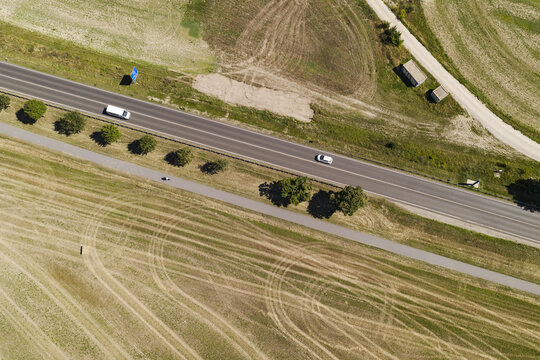 Aerial view of a road passing through open fields with scattered trees and vehicles driving in Berlin, Berlin, Germany.