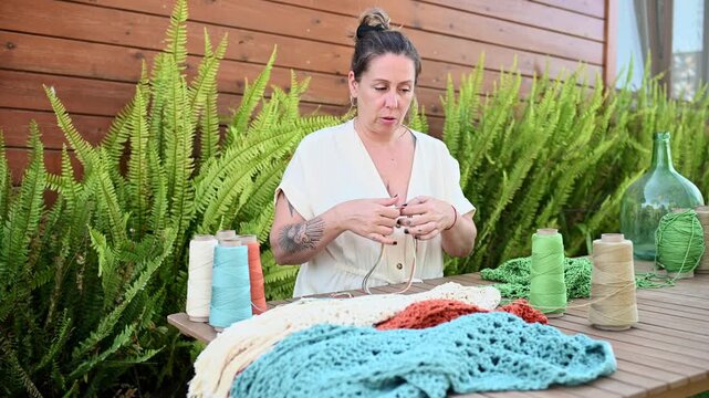 Woman crocheting green yarn with handmade crafts outdoors,  video 4k real time