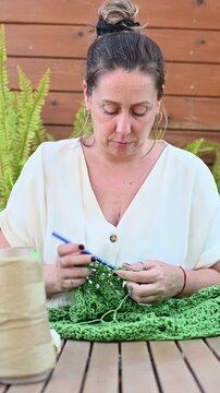 Female artisan crocheting handmade item with yarn outdoor