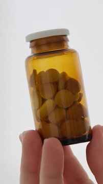 Female hand holding small amber glass jar filled with yellow health supplements womens health care vitamins d3 magnesium concept vertical slow motion video stock
