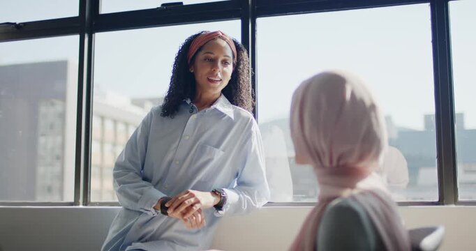 African American woman leaning on sill speaking gesturing at office while pink hijab peer listening