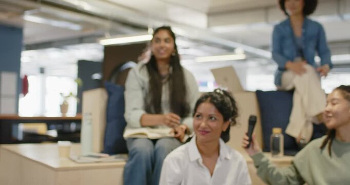 Diverse coworkers watching presenter passing mic while green-sweater speaker answering for team