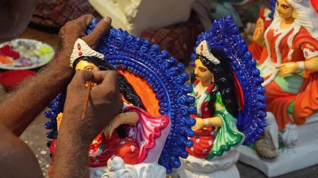 Close-up documentary view of a Kumartuli artist hand-painting a traditional religious murti inside an artisan workshop in Kolkata.