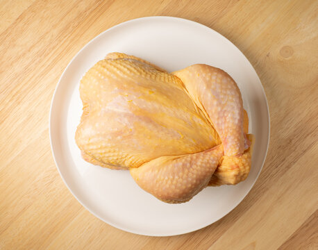 Raw whole chicken on white plate preparing for cooking