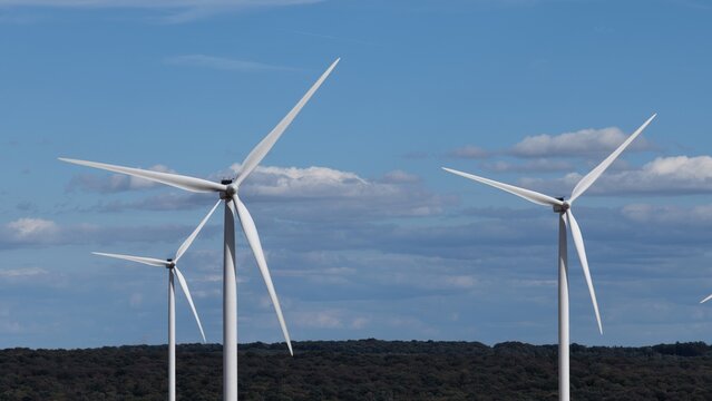 vue a&eacute;rienne en gros plan des &eacute;oliennes et du parc &eacute;olien d'Ottange en Moselle. Les pales et les nacelles blanches tournent sur un ciel bleu l&eacute;germent nuageux. Frrance septembre 2026 
