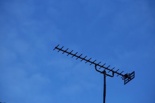 Television aerial antenna silhouetted against deep blue dusk sky