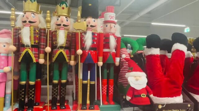 Vertical tall nutcracker lineup on shelf showing variety of painted soldiers and santa plush with crown details, Christmas decoration and gifts in shop