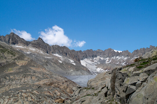 Panoramic view of the majestic Rh&ocirc;ne Glacier in the Swiss Alps surrounded by rugged rocky mountain peaks under a clear blue sky