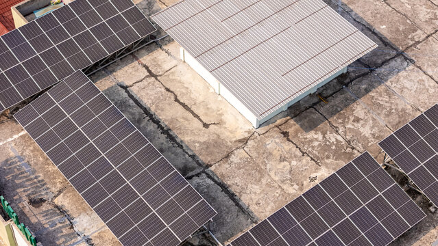 Aerial view of solar panels installed on a weathered concrete rooftop in Klaten, Central Java, Indonesia.