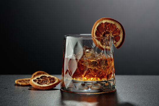 Whiskey based Old Fashioned cocktail garnished with a dried orange slice.