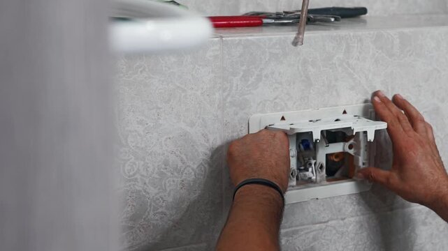 Plumber installing internal flush components inside a concealed toilet cistern during bathroom installation