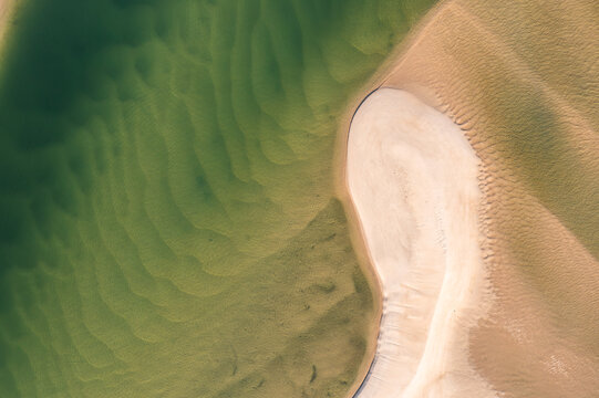 Aerial view of a sandbank surrounded by shallow turquoise water with intricate ripple patterns in the sand and clear water in Noosa Heads, Queensland, Australia.