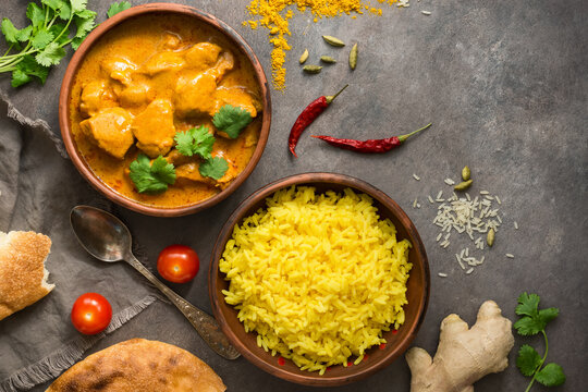 Chicken Tikka Masala with basmati rice on a dark grunge background, top view, flat lay. Traditional spicy Indian food.