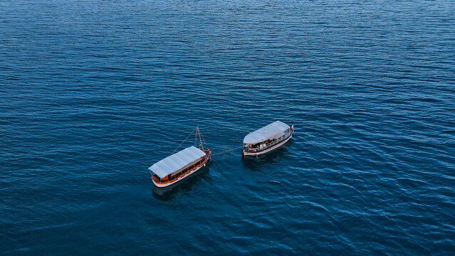 Aerial view of two wooden boats with white canopies floating on the deep blue sea at Ada Bojana, Ulcinj Municipality, Montenegro.