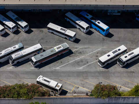 Aerial view of multiple buses parked in a terminal area with marked parking spaces and surrounding greenery Evora, Evora District, Portugal.