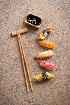 Set of Japanese sushi with soy sauce and chopsticks on a brown stone background, top view, flat lay, copy space