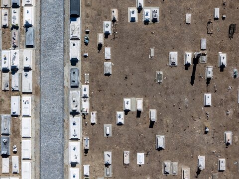 Aerial view of the cemetery in Evora with rows of white stone graves and a cobblestone pathway set against dry earth in Evora, Evora District, Portugal.