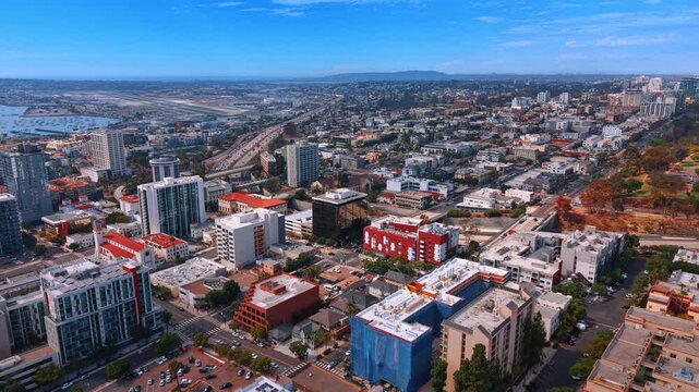 Wide aerial view of the San Diego cityscape, airport runway and marina. Daytime shot of city apartment buildings next to the Interstate 5 highway.