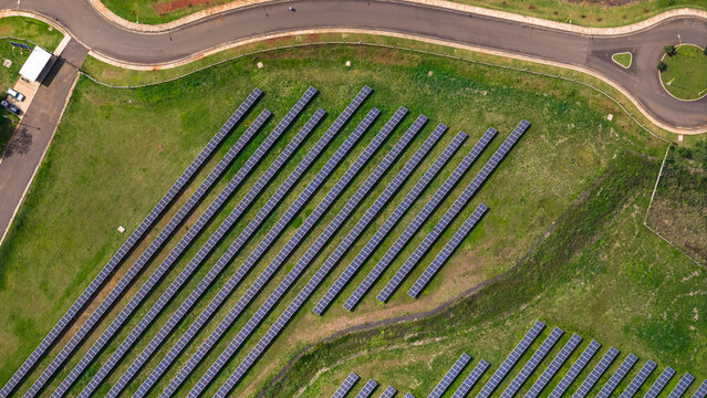 Aerial view of rows of solar panels installed in a grassy field next to a paved road in Posadas, Misiones Province, Argentina.