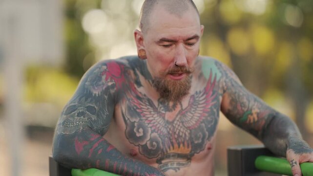 Tattooed man training hard on parallel bars
