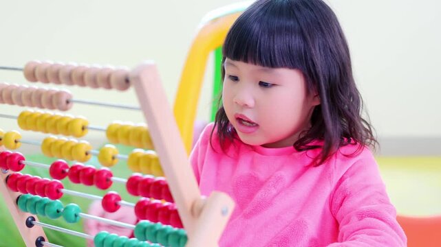 Happy toddler focused on education learning with wooden abacus toy for early development, preschool child curiosity playing colorful beads math skills