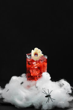 Spooky Halloween cocktail with ice and ghost decoration on cobweb