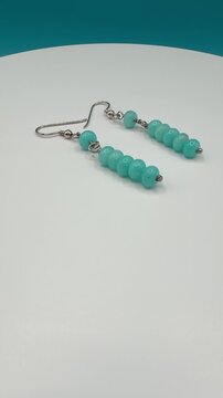 Handmade earring with natural amazonite gemstone beads on jewelry display stand, advertising shot for jewelry brand