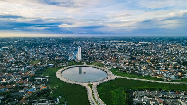 Aerial view of the circular lake at Summarecon Bekasi surrounded by dense urban development and residential rooftops in Bekasi Barat, West Java, Indonesia.