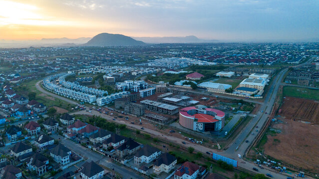 Aerial view of residential developments, a distinctive circular building, and roads in the urban landscape of Abuja, Federal Capital Territory, Nigeria.