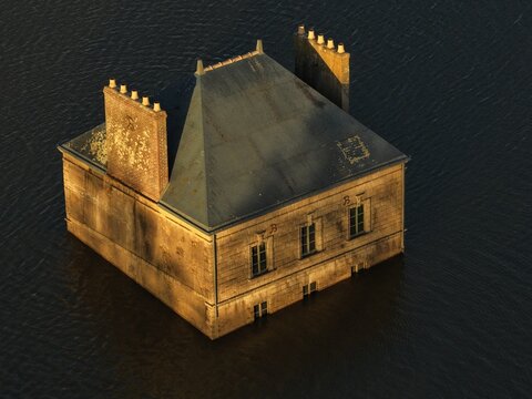 Coueron, France - 29 December 2025: Aerial view of La Maison dans la Loire, a surreal house sculpture partially submerged in the Loire River, illuminated by warm golden hour light.