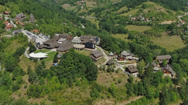 Aerial view of Drvengrad Kustendorf ethno village on Mokra Gora, Serbia, surrounded by green hills and mountains, 4k