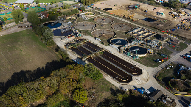 Farnham, United Kingdom - 15 September 2026: Aerial view of the Waste Water Treatment Works featuring circular sedimentation tanks, rectangular aeration basins, and surrounding green space.